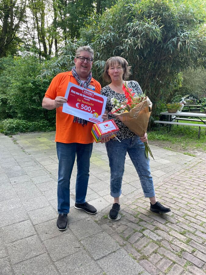 2 personen poseren met bloemen en cheque met daarop 500 euro